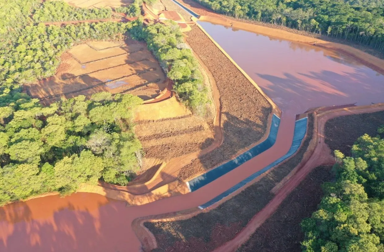 Vista aérea de barragem de rejeito com lagoa e canal extravasor revestido