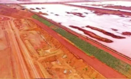 Vista aérea de maciço de barragem com faixa gramada entre o reservatório e a área de terraplenagem
