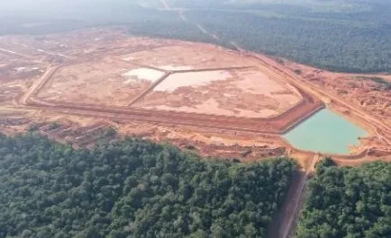 Vista aérea de grande área de reservatório com lagoa esverdeada, cercada por floresta