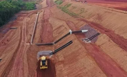 Vista aérea de área de terraplenagem com canais de drenagem revestidos e trator de esteira em operação