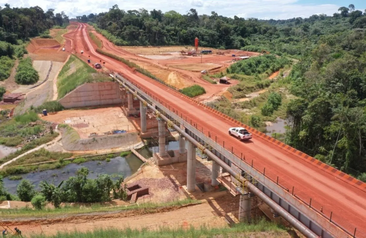Vista aérea da Estrada AWA: ponte em concreto sobre igarapé, estrada de terra vermelha e floresta ao redor
